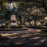 Historic Savannah square with monument and oak trees draped in Spanish moss at dusk, a scenic and storied location featured on Savannah ghost tours in the Savannah historic district.